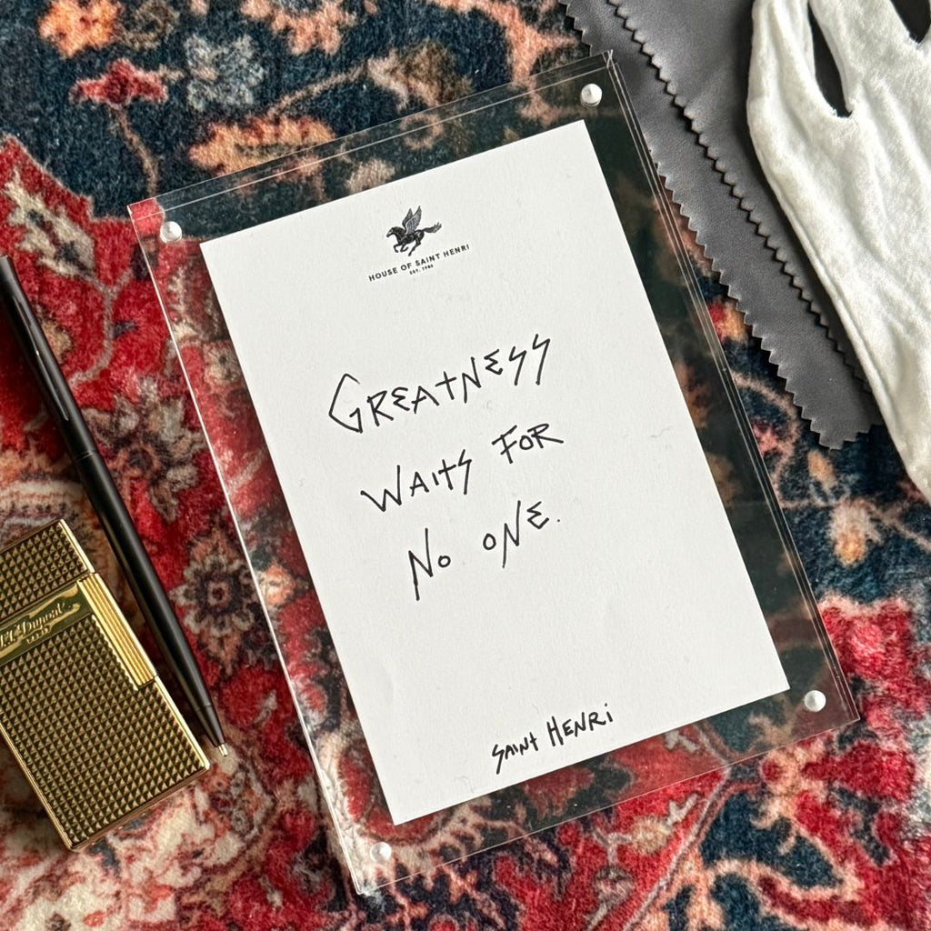 Note with 'Greatness waits for no one' quote on a patterned surface